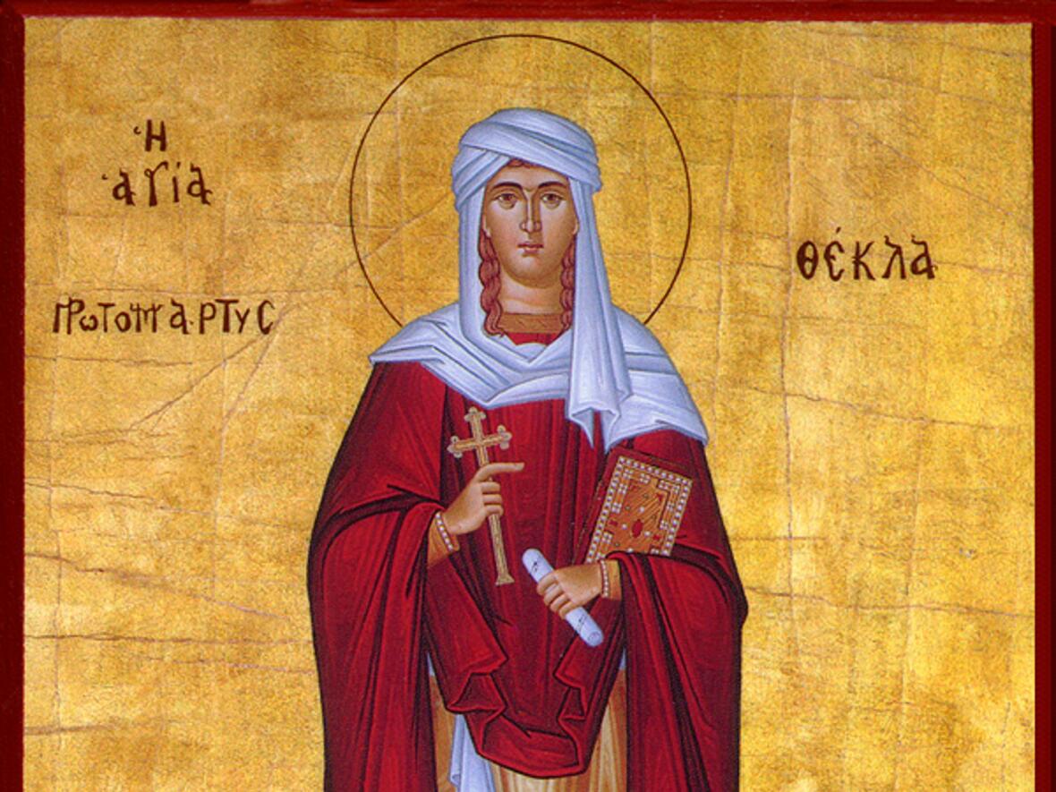Heilige Thekla in rotem Gewand mit Kreuz und Buch. Byzantinische Ikone vor goldfarbenem Hintergrund.